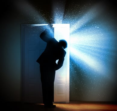 Executive peeking through door with light shining through