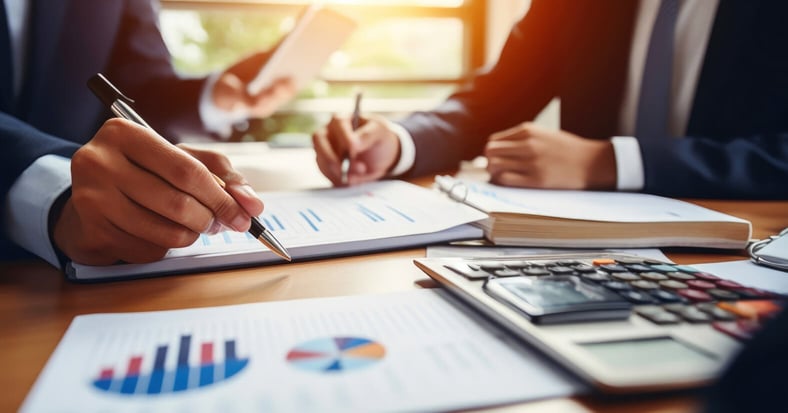 Financial Forecasting for Uncertain Times: A Guide for Executives - Two Men Sitting At Table Analyzing Charts With A Calculator 